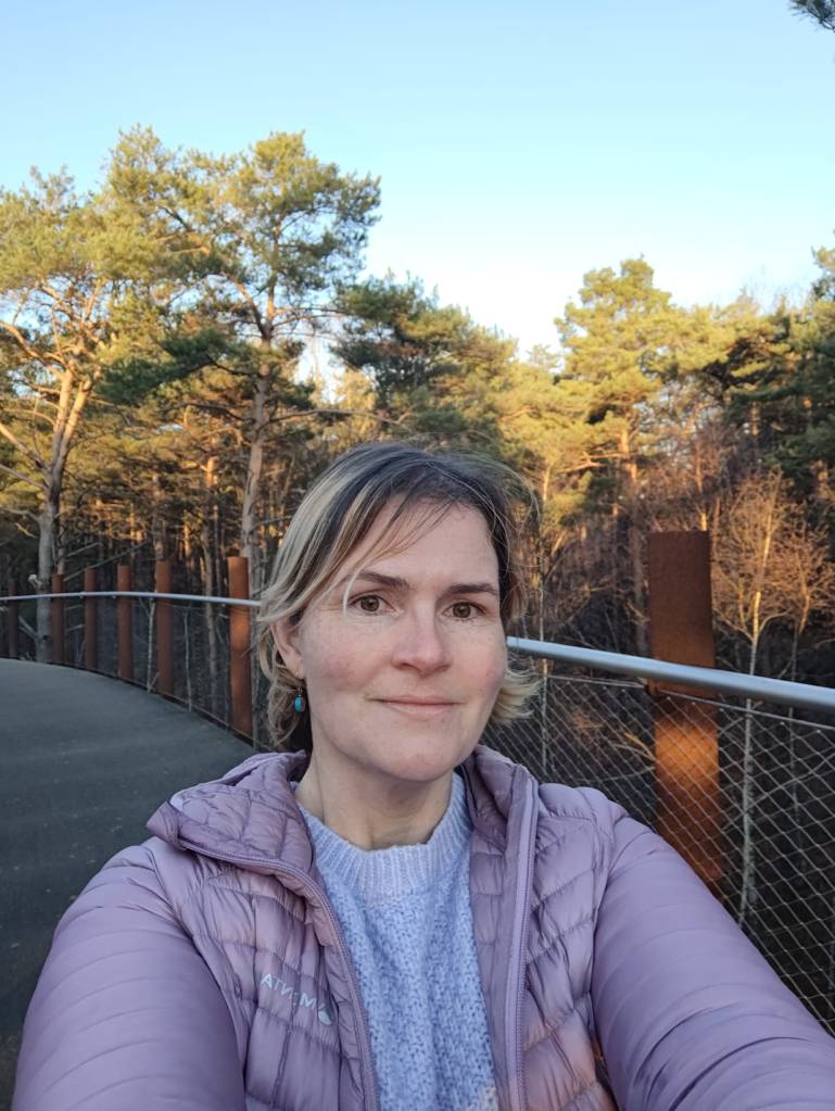 A photo of Claire on an elevated walkway between trees.